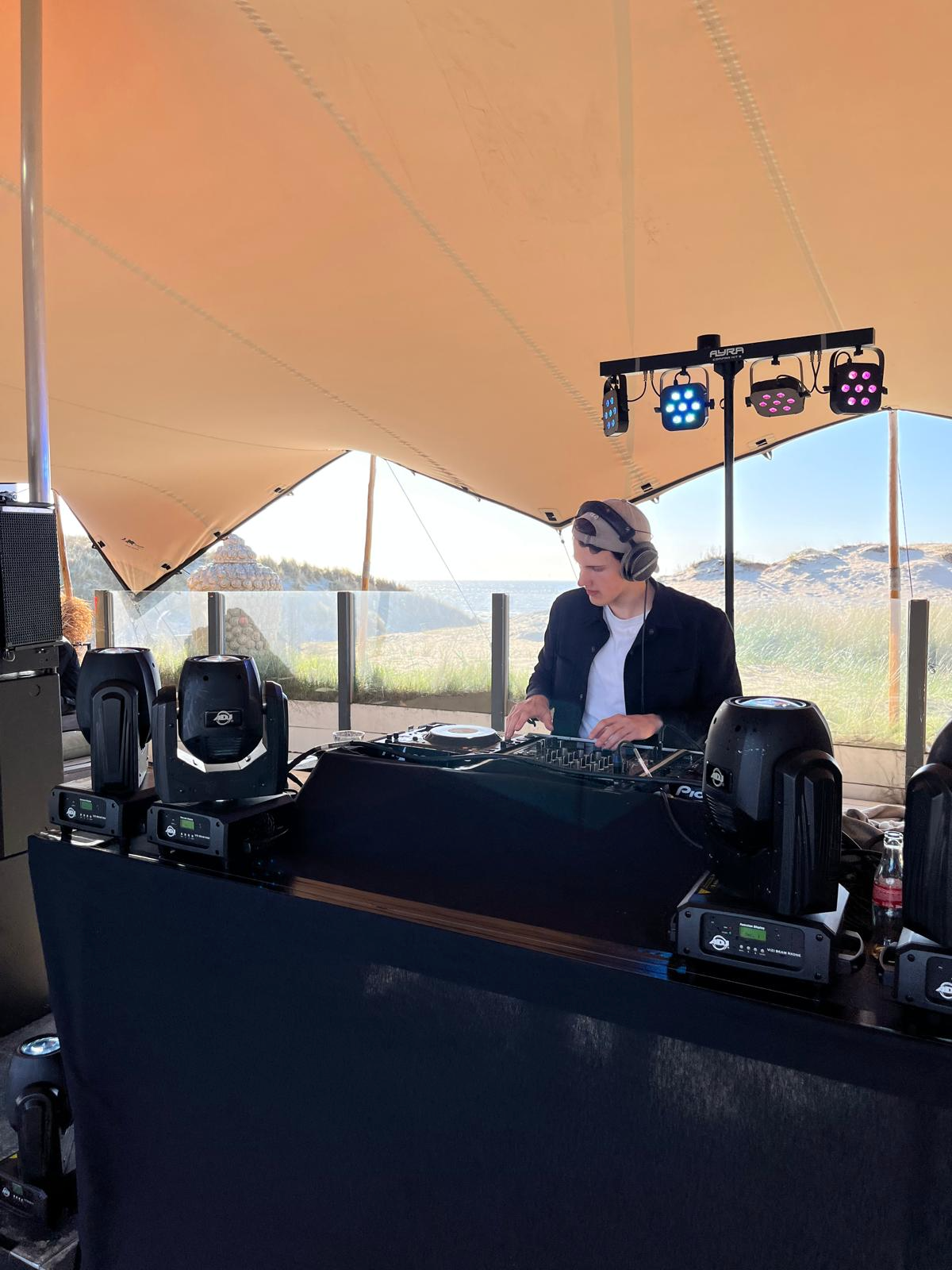 DJ Max achter de booth tijdens een sfeervolle show bij zonsondergang