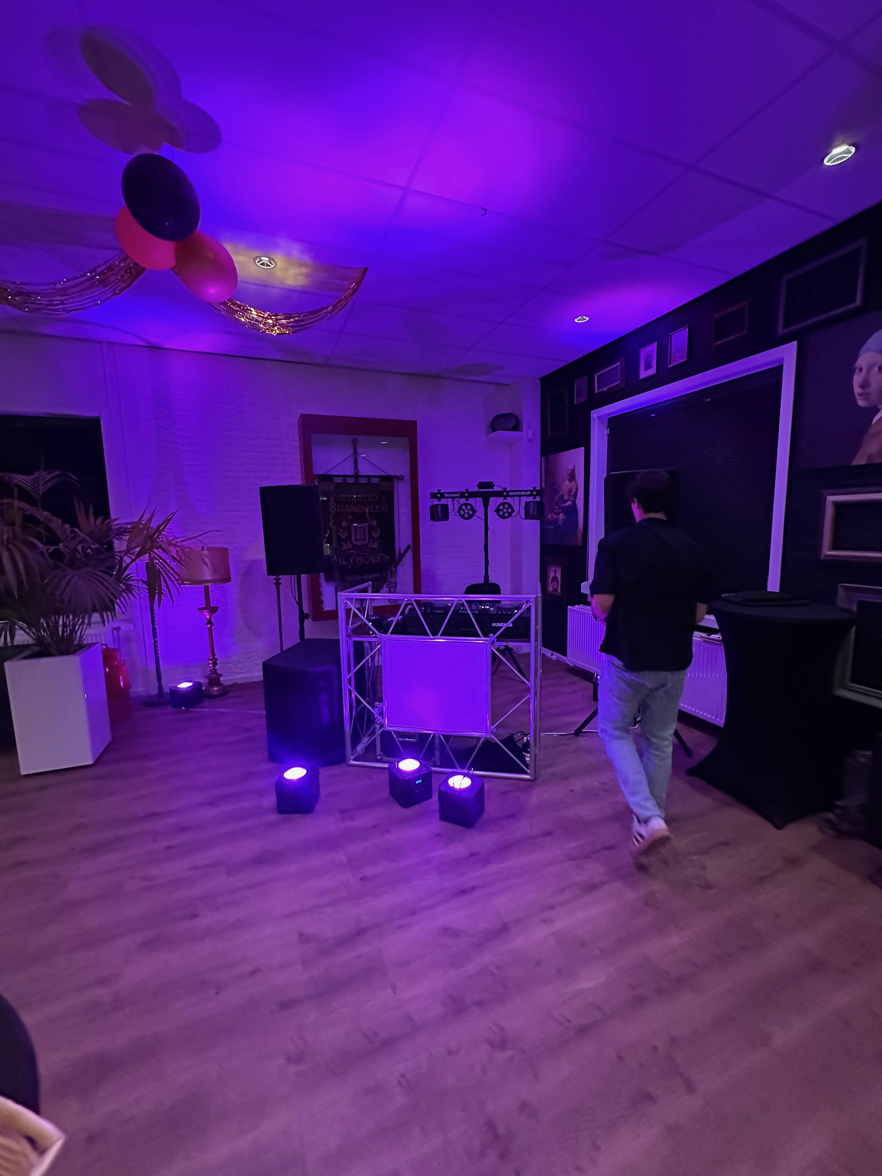 Paarse sfeerverlichting en DJ-booth bij een verjaardagsfeest
